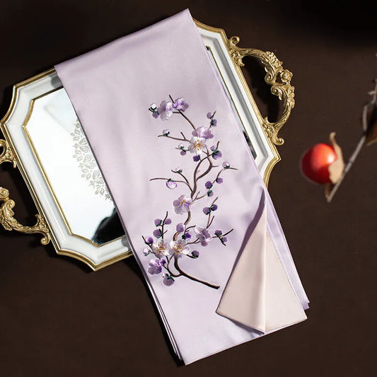 Embroidered fabric with floral design on a decorative tray against a dark background