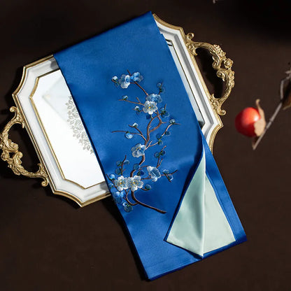 Blue embroidered fabric with floral design on a decorative tray against a dark background
