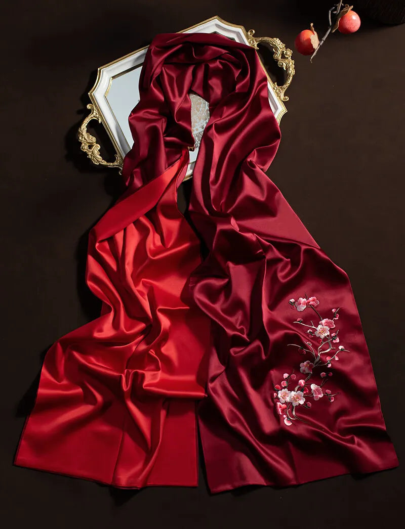 Red satin fabric with floral embroidery on a dark background