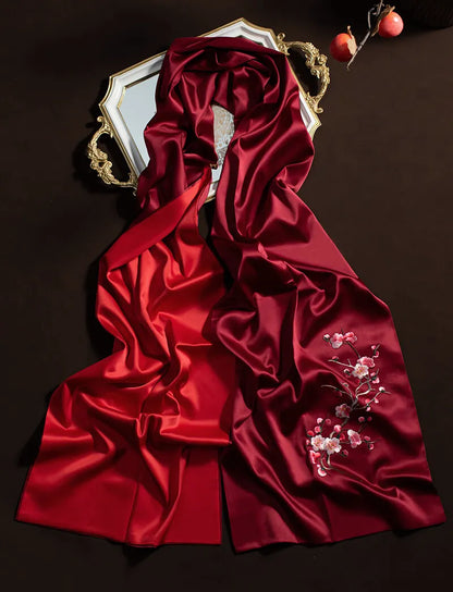 Red satin fabric with floral embroidery on a dark background