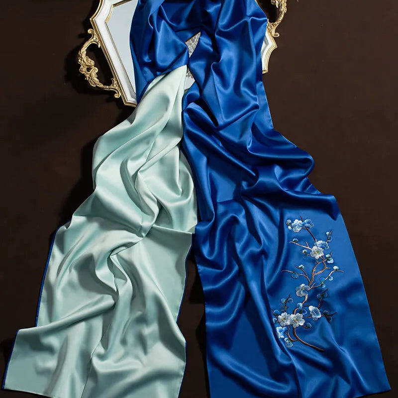 Two pieces of fabric, one light green and one blue with floral embroidery, on a dark background.