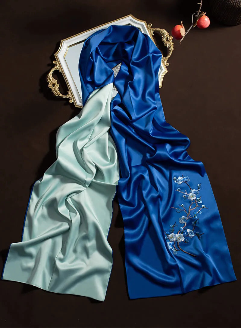 Two pieces of fabric, one light green and one blue with floral embroidery, on a dark background.