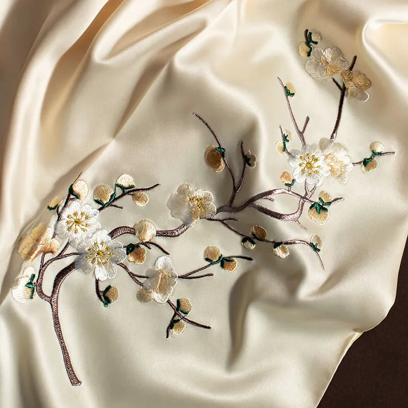 Embroidered floral branch on a satin fabric background