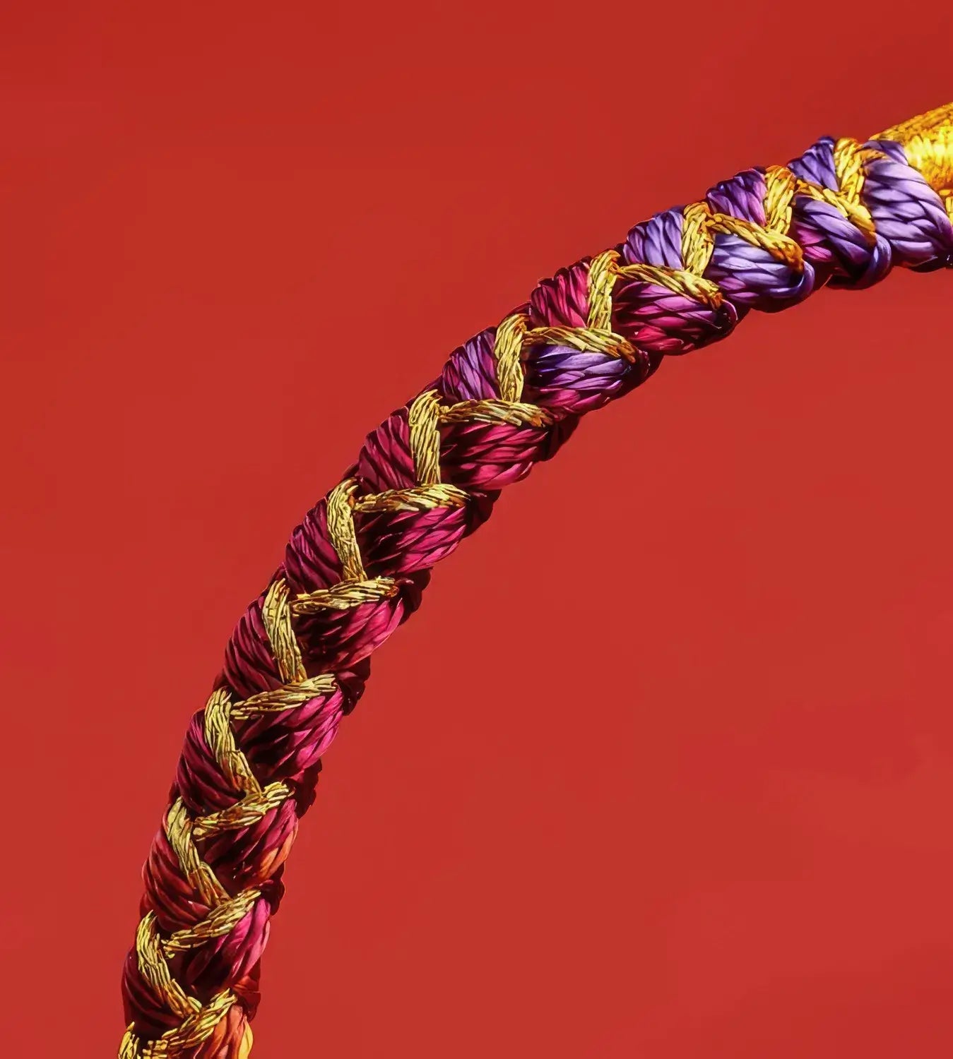 Braided cord with gold, purple, and red colors on a red background