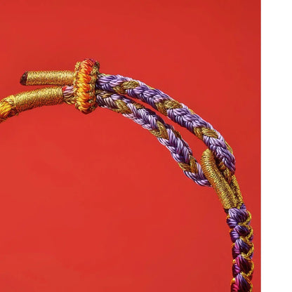 Braided purple and gold cord on a red background