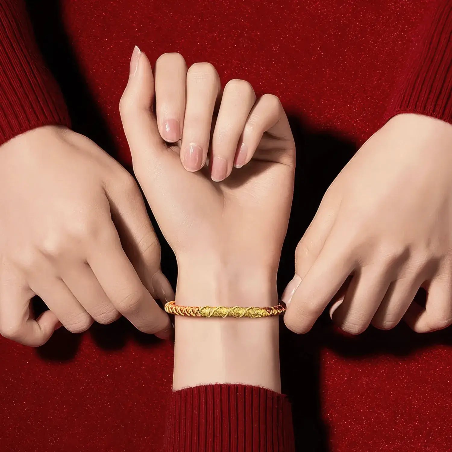 Close-up of a hand wearing a gold bracelet with two other hands on a red background