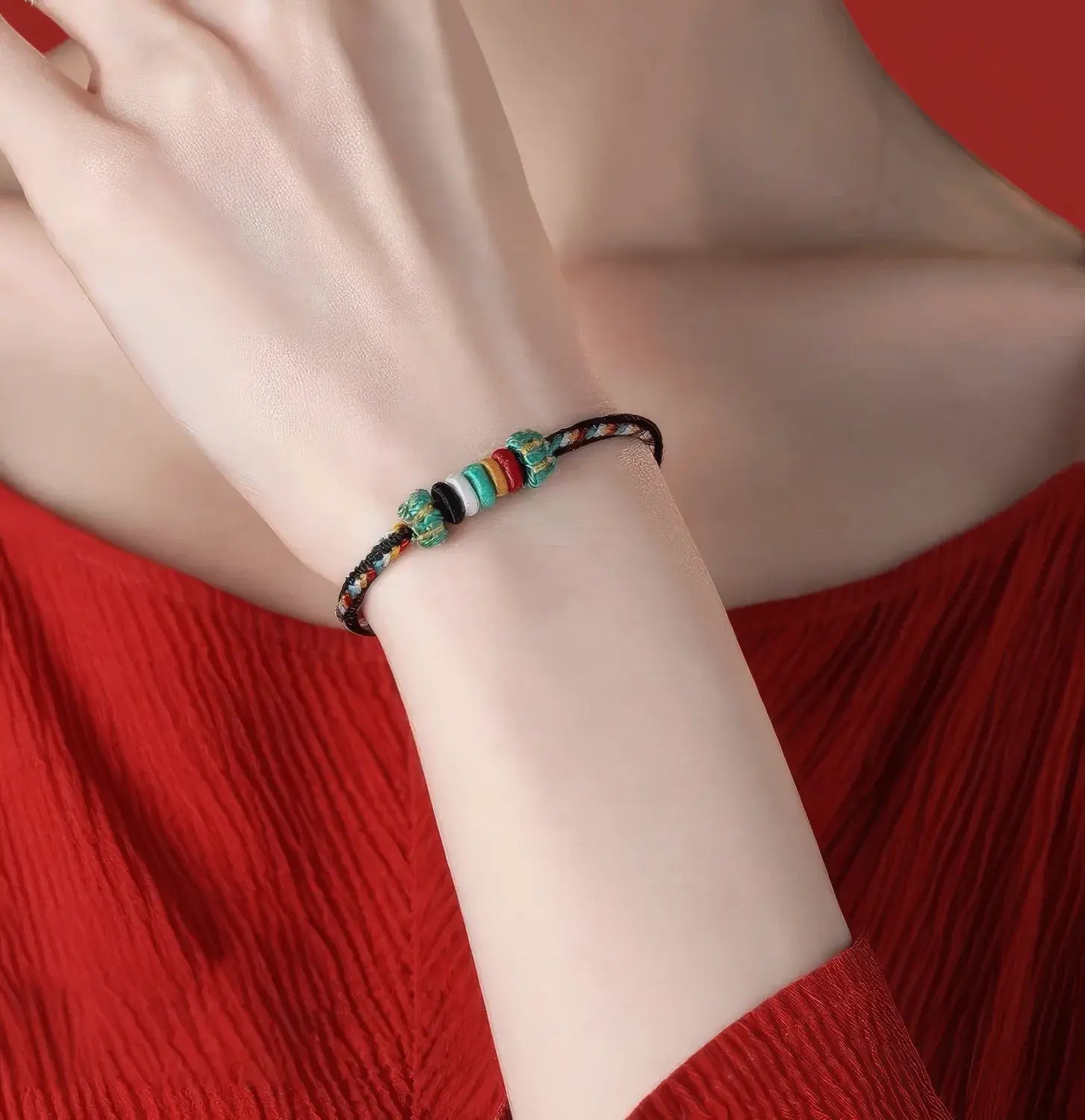 Colorful beaded bracelet on a wrist with a red background