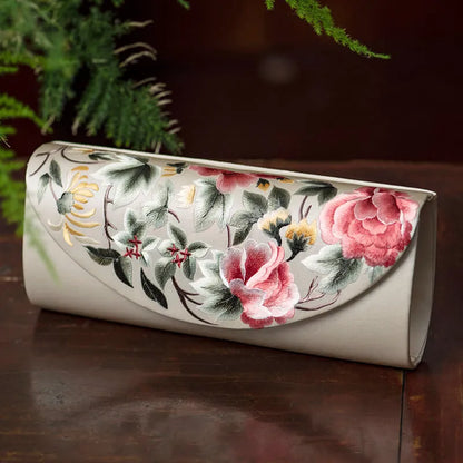 Floral embroidered clutch on a wooden surface with greenery in the background