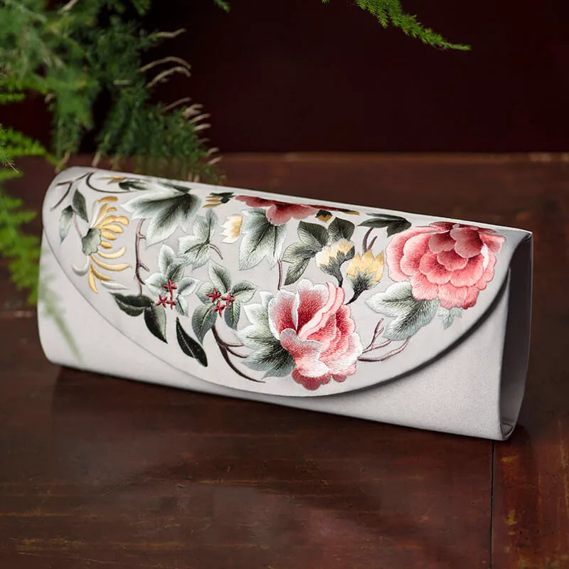 Floral-patterned clutch on a wooden surface with greenery in the background