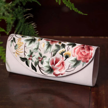 Floral embroidered clutch on a wooden surface with greenery in the background