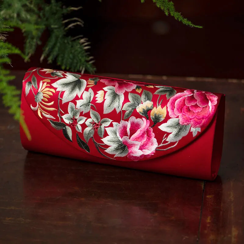 Red clutch with floral embroidery on a dark surface
