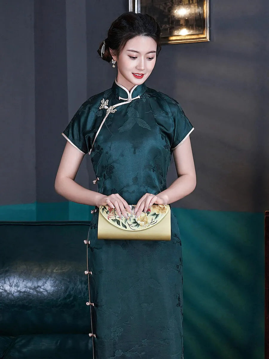 Woman in a green traditional dress holding a gold clutch against a dark background