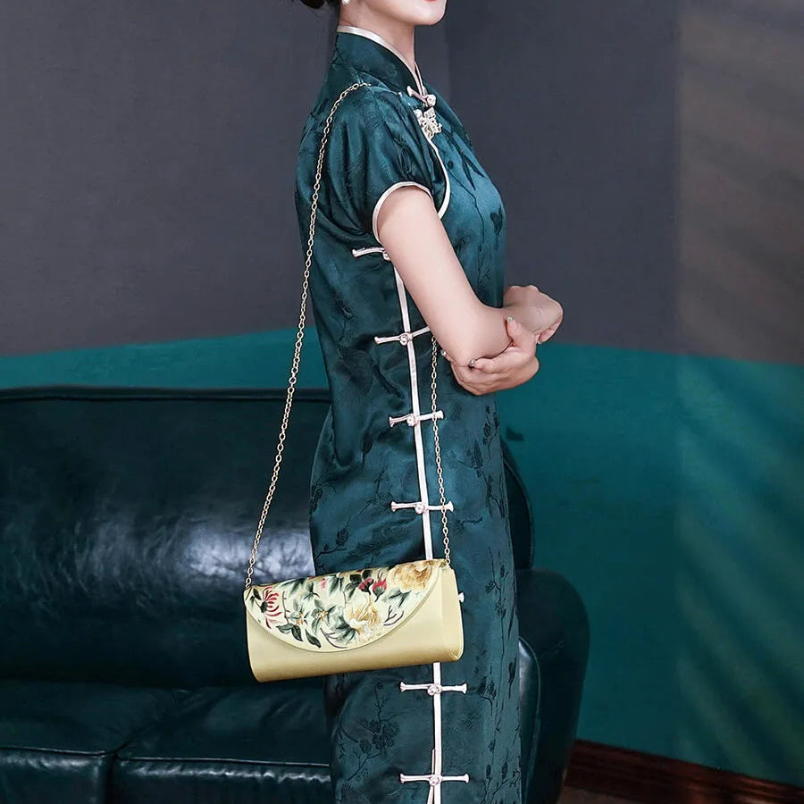 Woman in a green traditional outfit holding a yellow handbag in a room with a blue couch and framed pictures.