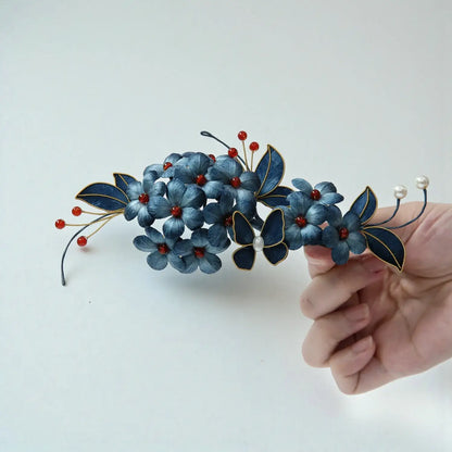 Decorative headband with blue flowers and butterflies held by a hand on a light background