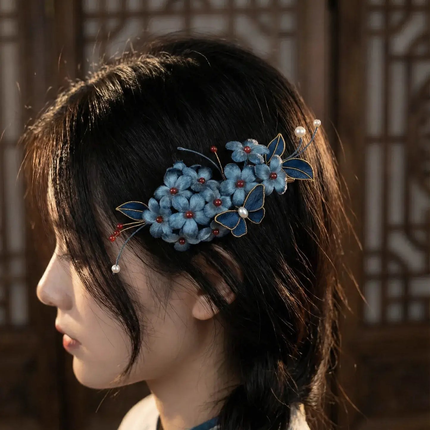 Woman with a blue floral hair accessory in her dark hair against a warm-toned background