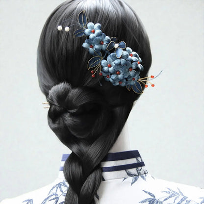 Hair styled in a braid with decorative hairpin featuring blue flowers and red berries on a plain background.
