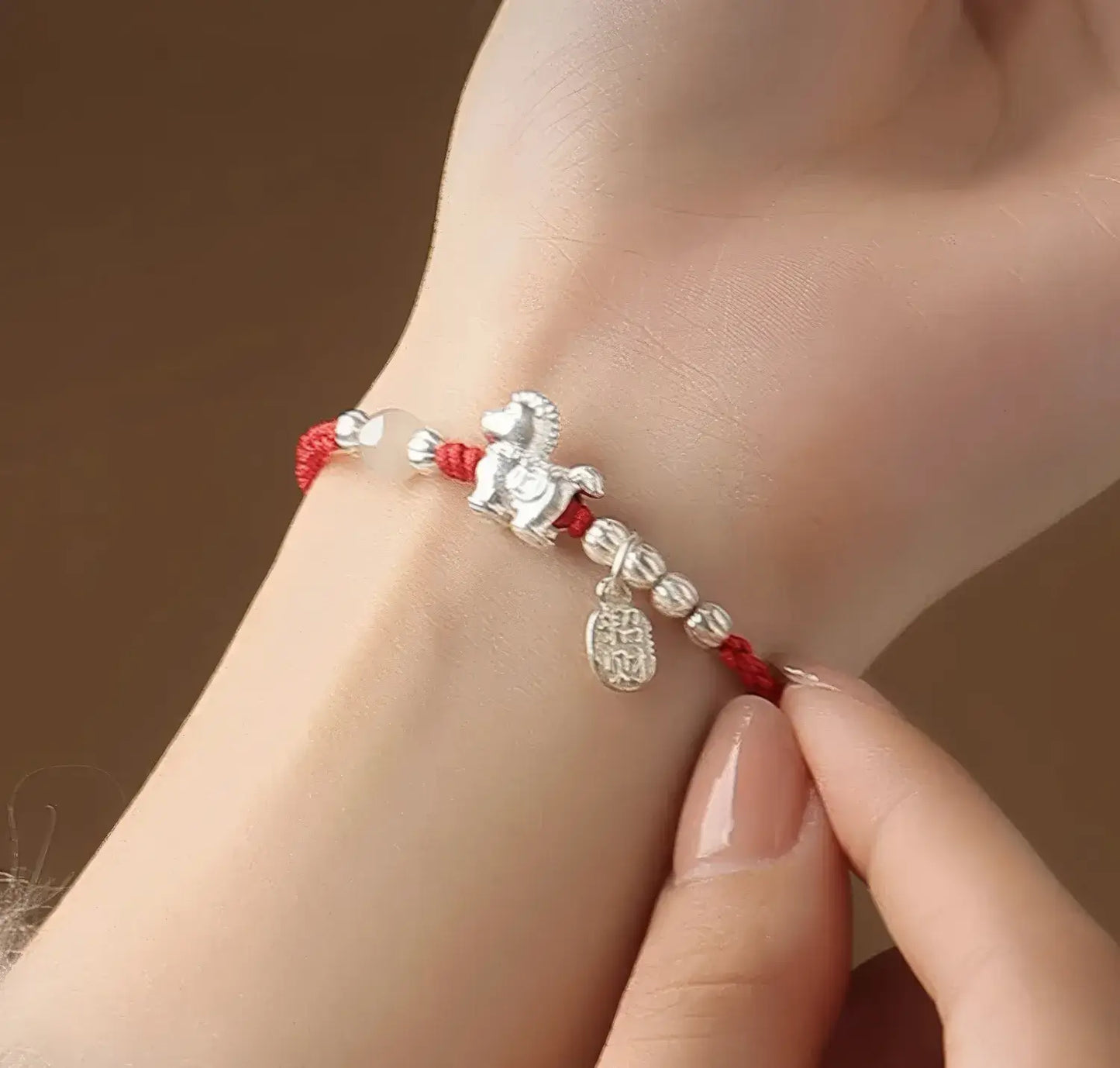 Bracelet with horse charm on a wrist against a brown background
