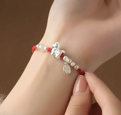 Bracelet with horse charm on a wrist against a brown background