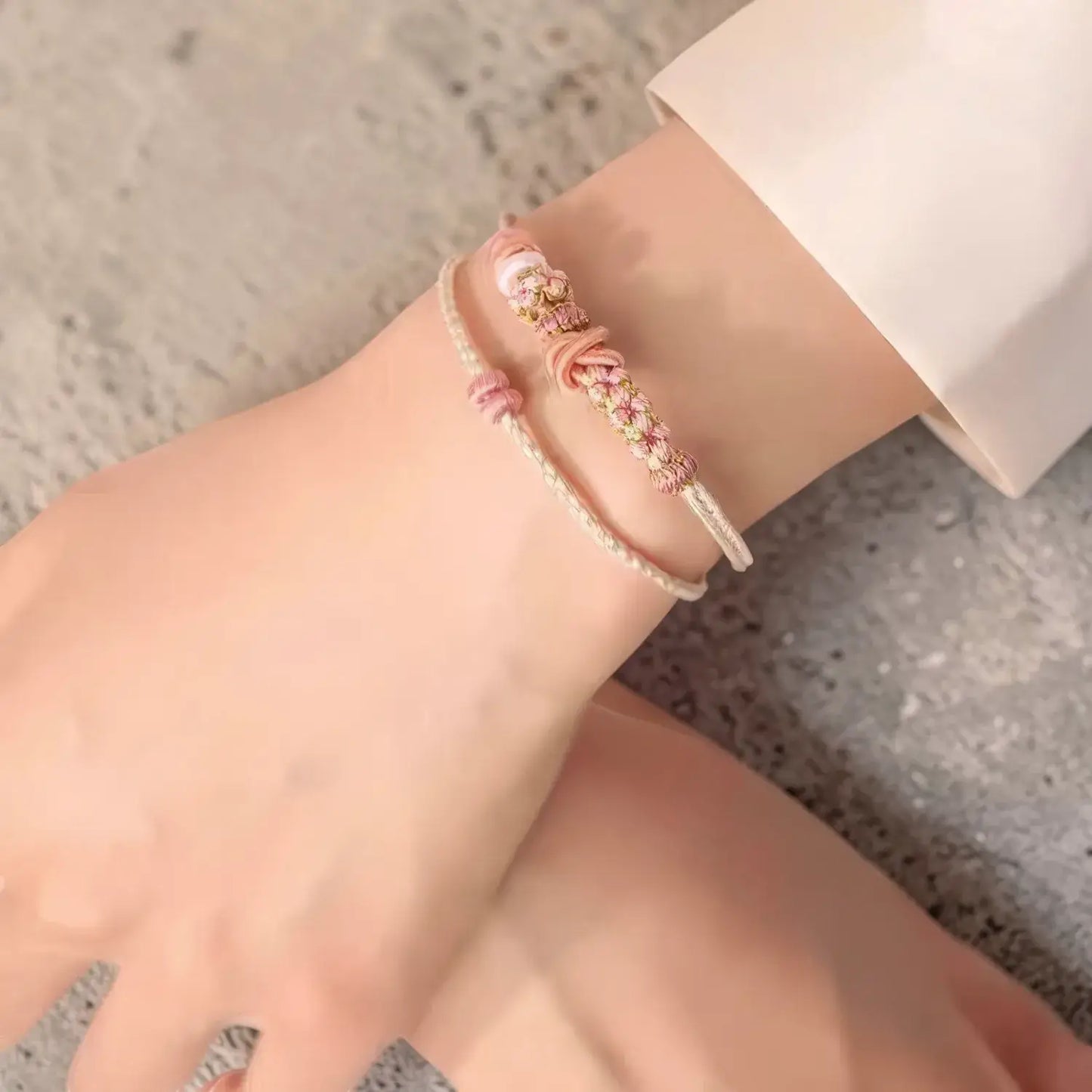 Close-up of a wrist wearing a delicate bracelet on a neutral background