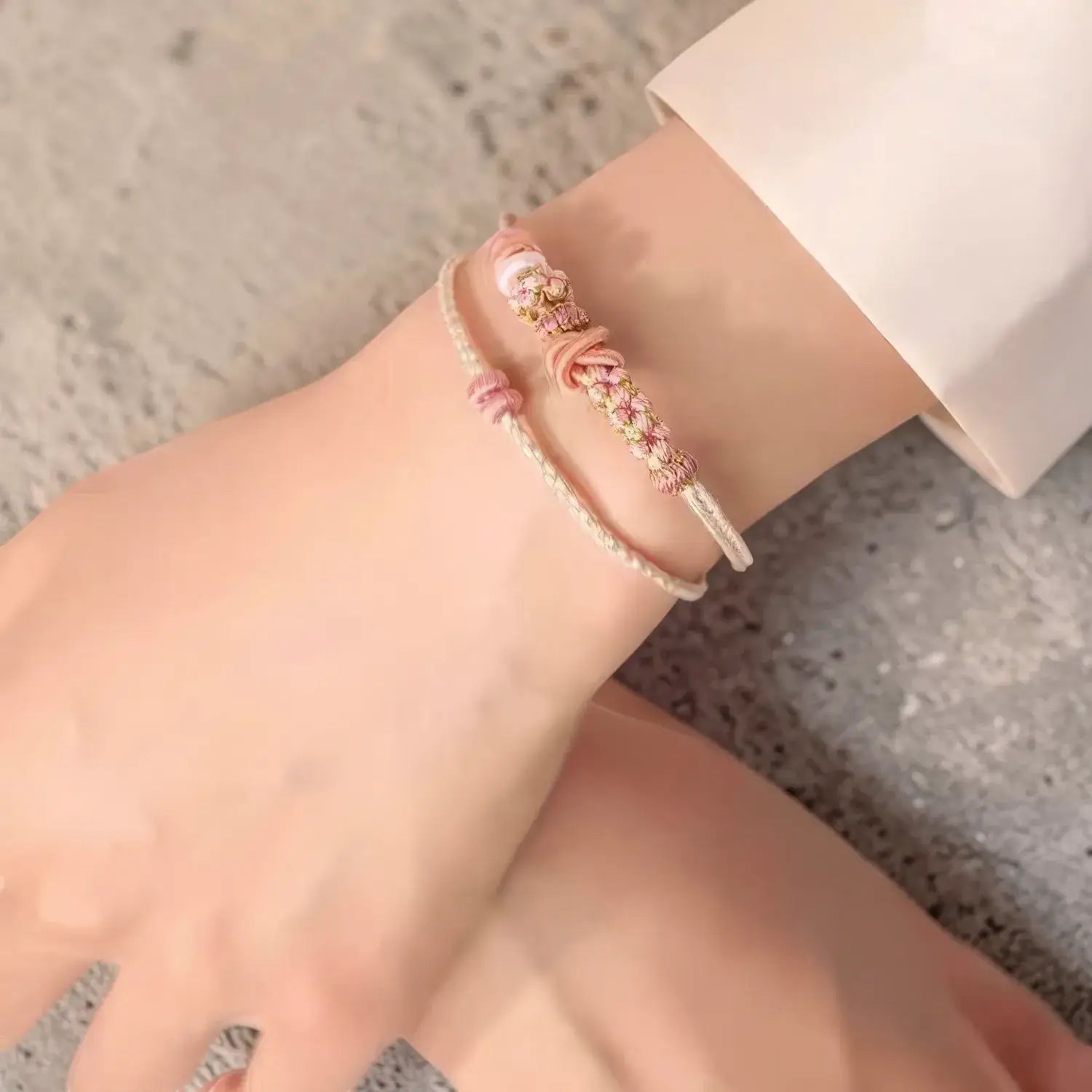 Close-up of a wrist wearing a delicate bracelet on a neutral background