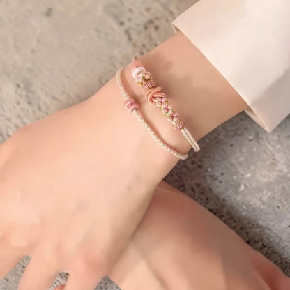 Close-up of a wrist wearing a delicate bracelet on a neutral background