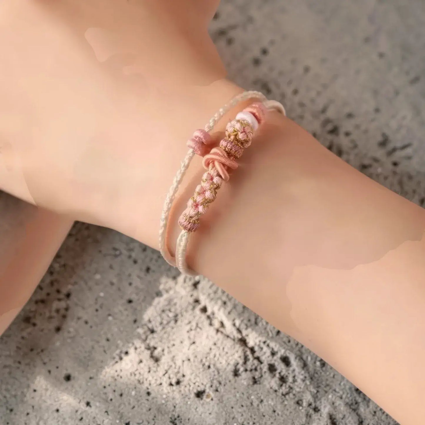 Close-up of a wrist wearing a pink beaded bracelet on a textured surface