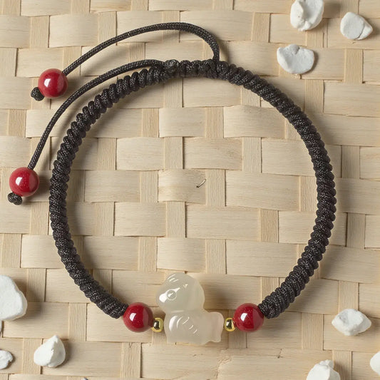 Black braided necklace with red beads and a white duck charm on a woven mat background