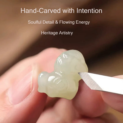 Hand-carved jade piece with a tool, held by a hand, on a blurred background.