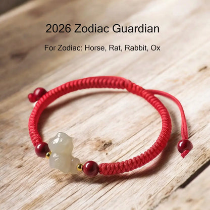 Red cord bracelet with a white stone charm on a wooden surface, labeled '2026 Zodiac Guardian' for specific zodiac signs.