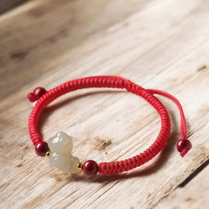 Red bracelet with a white stone charm on a wooden surface
