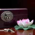 Decorative lotus flower with a jewelry box and keychain on a reflective surface.
