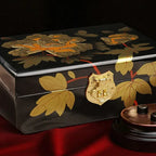 Decorative black box with gold leaf patterns and a gold lock on a red background