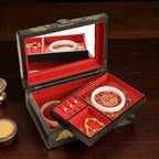 Open jewelry box with red interior displaying various pieces of jewelry on a wooden surface.