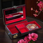 Open jewelry box with decorative interior on a wooden surface with pink flowers.