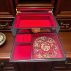 Decorative jewelry box with red interior and gold patterns on a wooden cabinet.