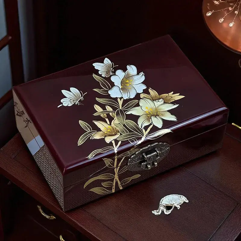 Decorative jewelry box with floral design and butterfly on a wooden surface.