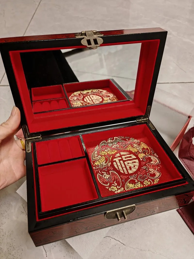 Decorative jewelry box with red and gold interior, held by a hand.