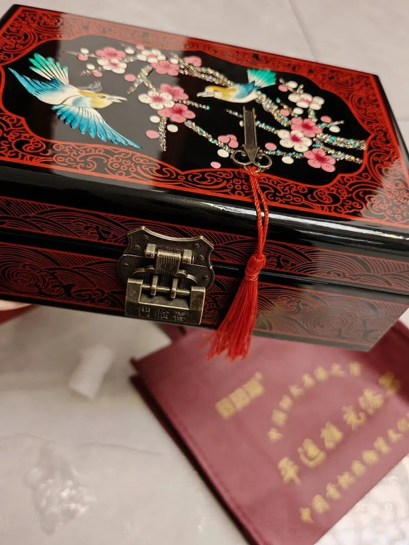 Decorative jewelry box with floral and bird design on a white surface