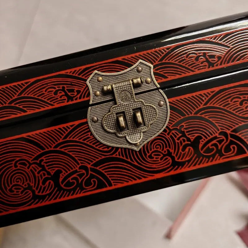 Decorative object with red patterns and a metallic emblem on a white background