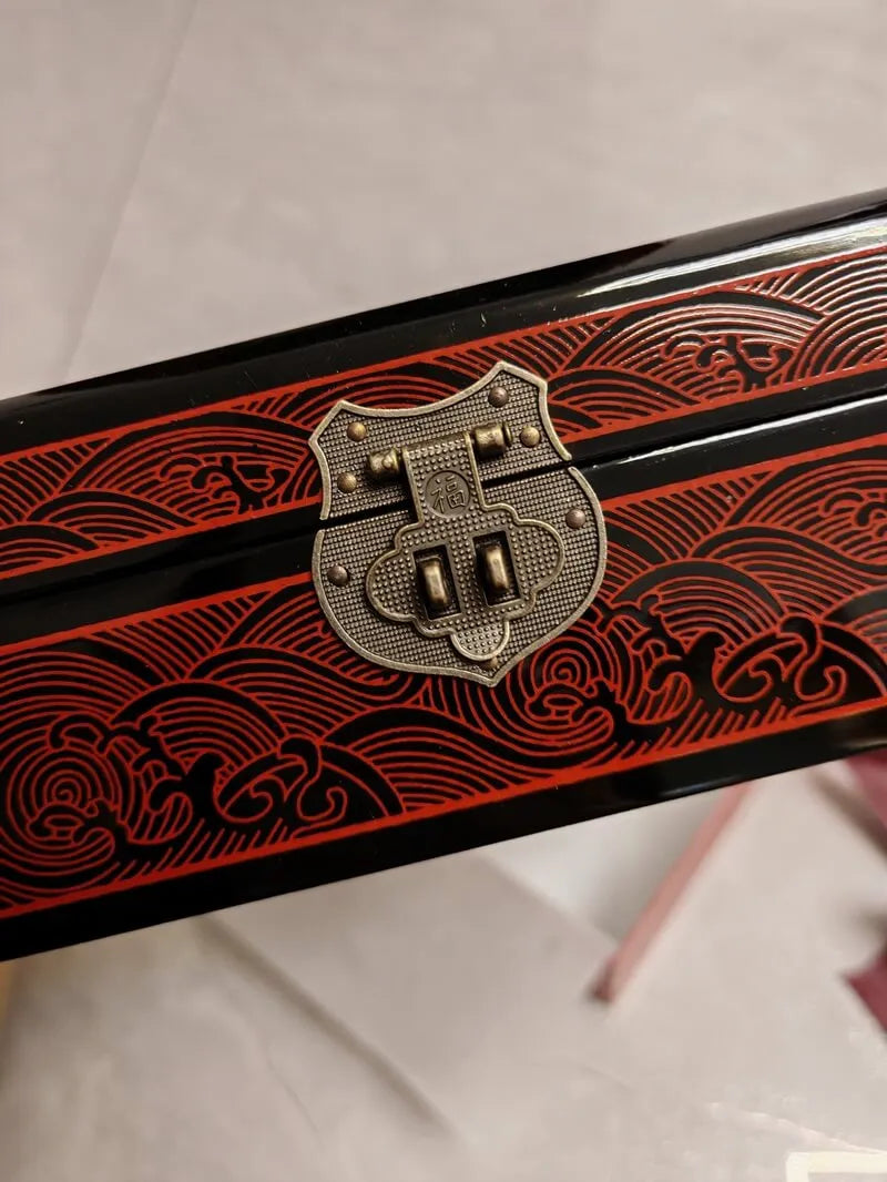 Decorative object with red patterns and a metallic emblem on a white background