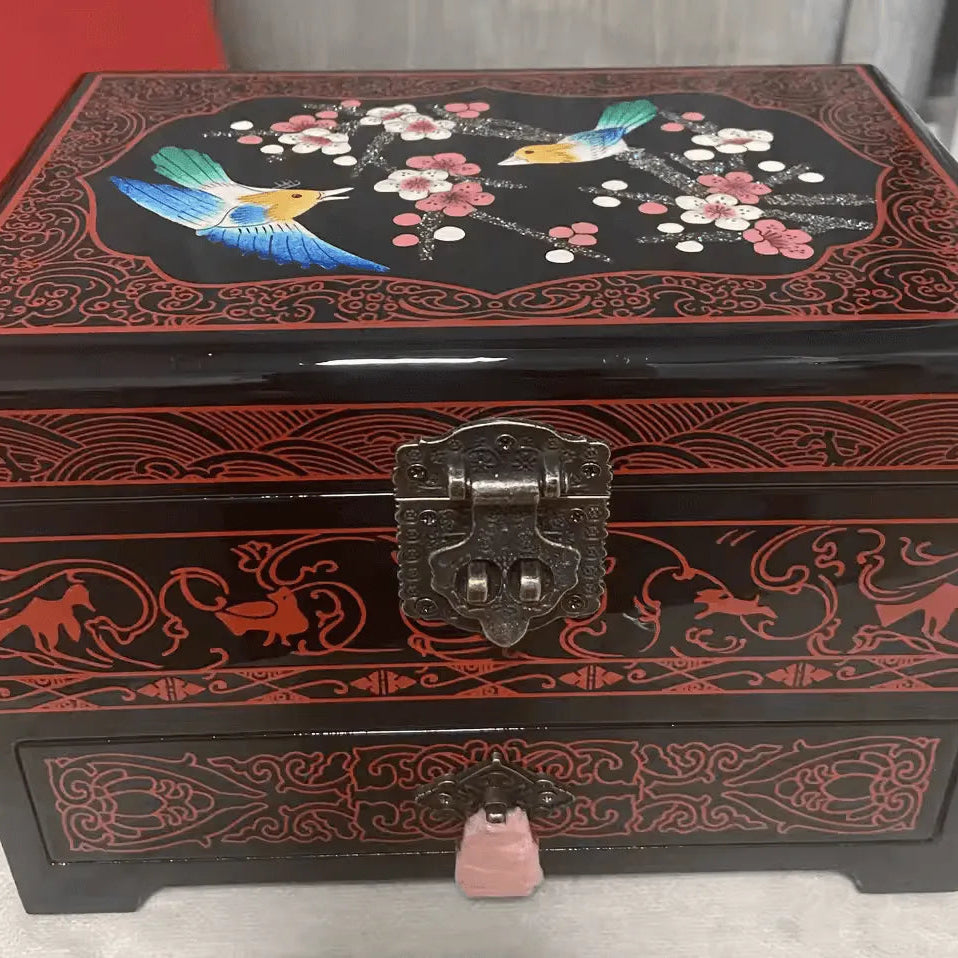 Decorative jewelry box with floral and bird design on a red background