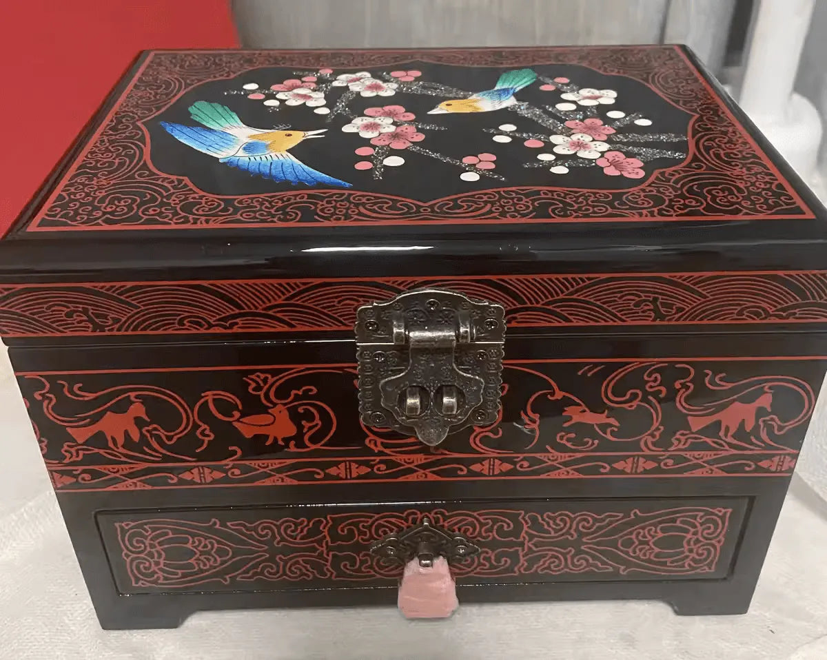 Decorative jewelry box with floral and bird design on a red background