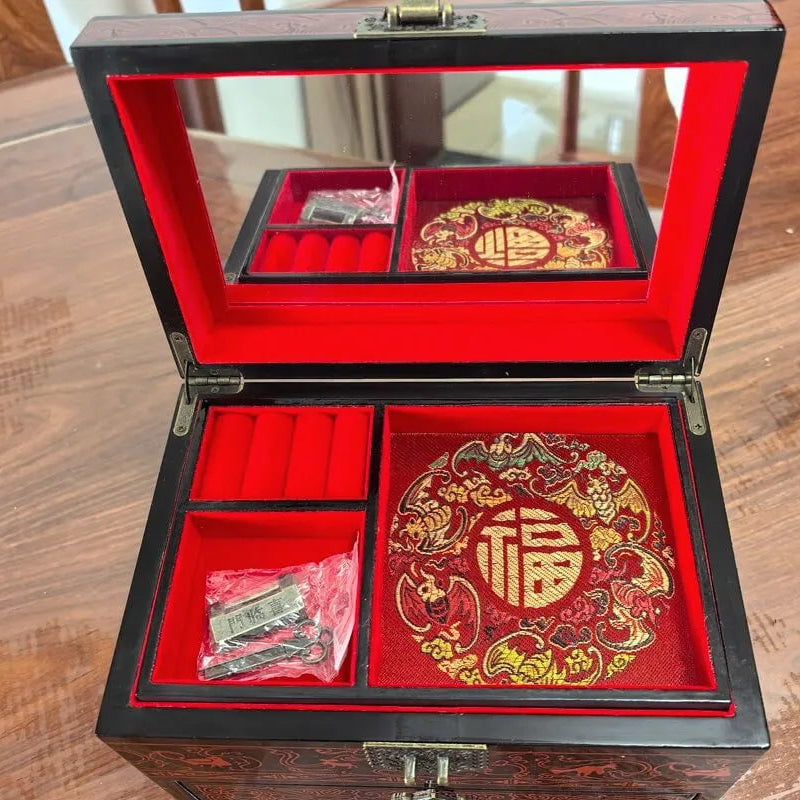 Decorative jewelry box with red interior and intricate designs on a wooden surface
