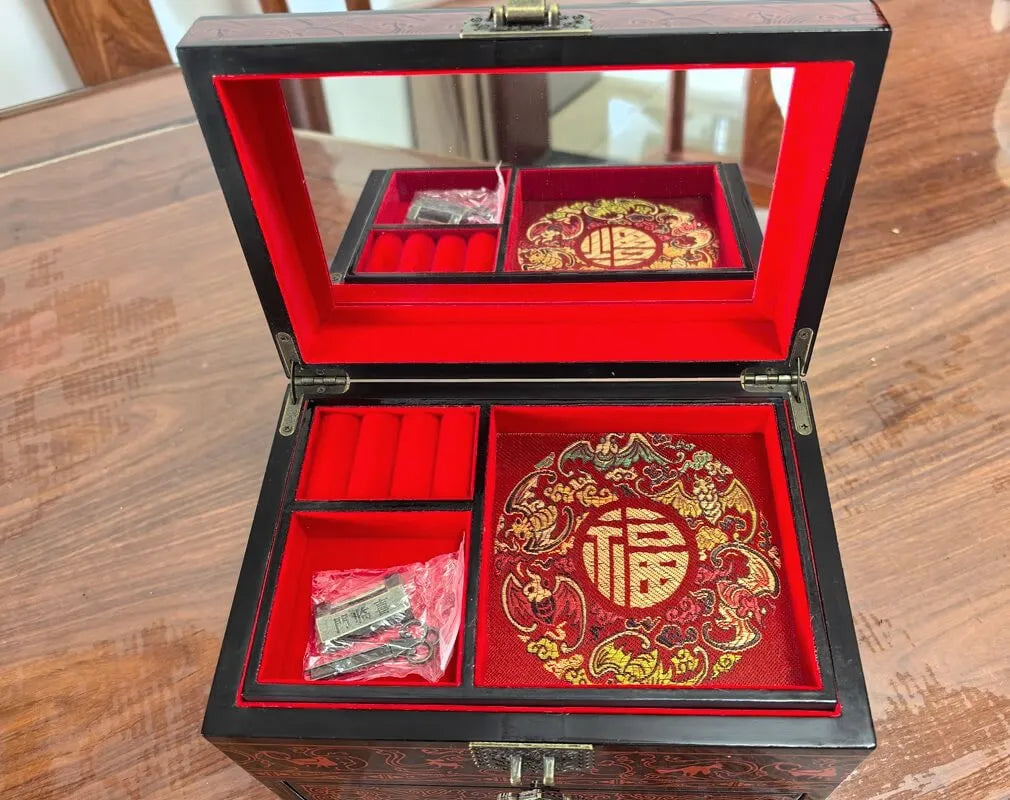 Decorative jewelry box with red interior and intricate designs on a wooden surface