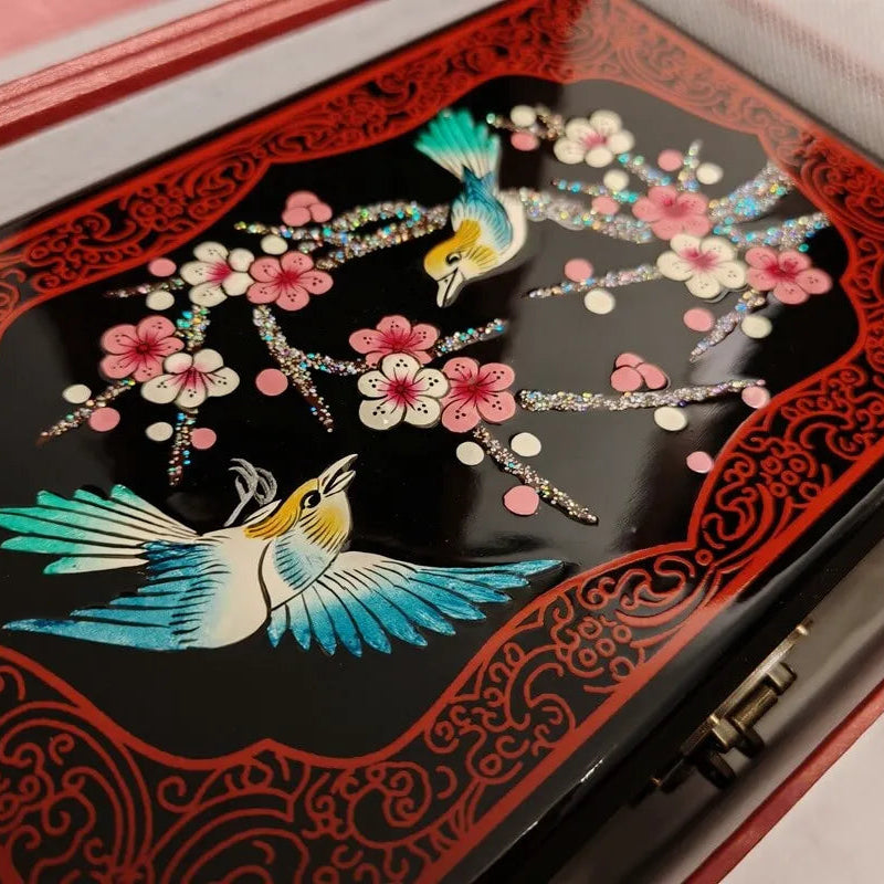 Decorative box with bird and floral design on a black background