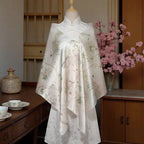 Mannequin wearing a floral dress with a cherry blossom branch in the background