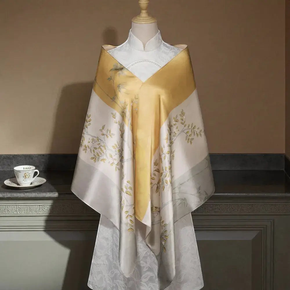 Mannequin wearing a gold and white floral patterned scarf with a cup and saucer on a table in the background.