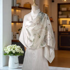 Mannequin wearing a floral scarf with a vase of flowers on a shelf in the background