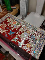 Decorative red box with floral and butterfly patterns on a cluttered desk.