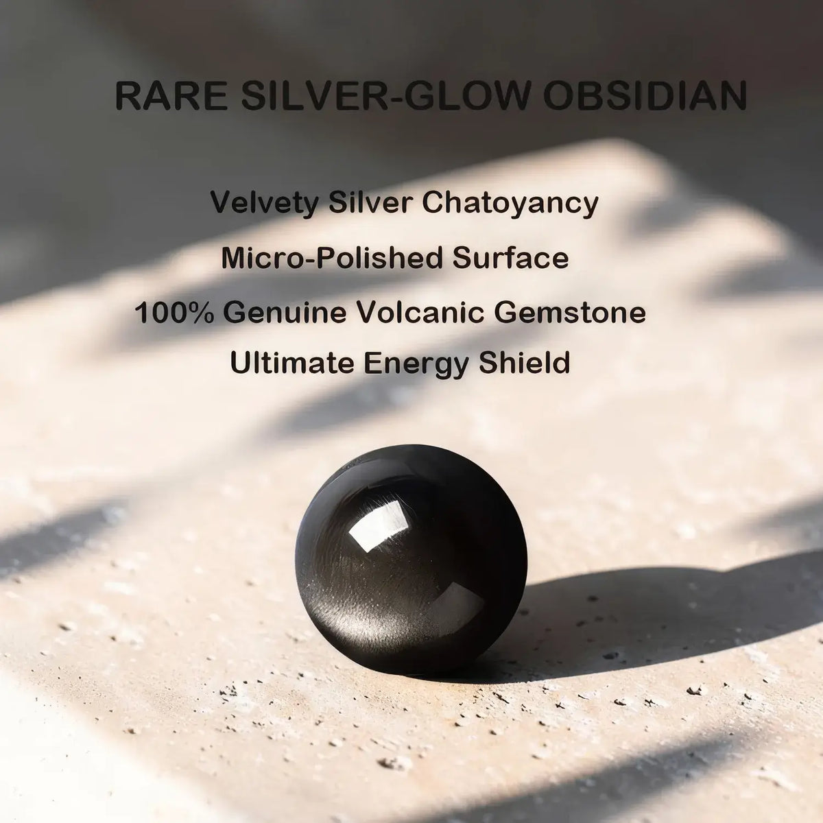 A single polished black obsidian gemstone sits on a textured stone surface with text above describing it as rare silver-glow obsidian, velvet silver chatoyancy, micro-polished surface, 100% genuine volcanic gemstone, and ultimate energy shield.